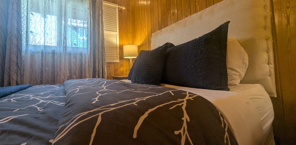 Queen bed made with comfortable bed and cozy lighting.