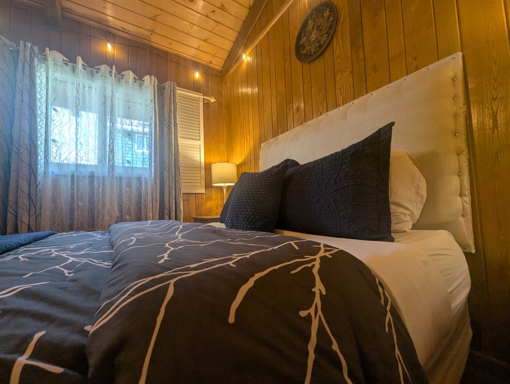 Queen bed made with comfortable bed and cozy lighting.