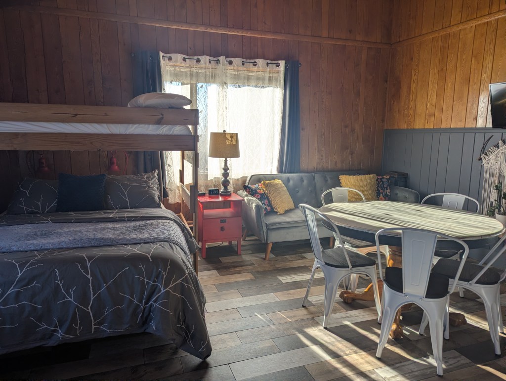 Large living space with table, couch, and bed with loft above