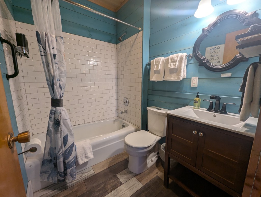 blue bathroom with tiled shower, vanity, and toilet