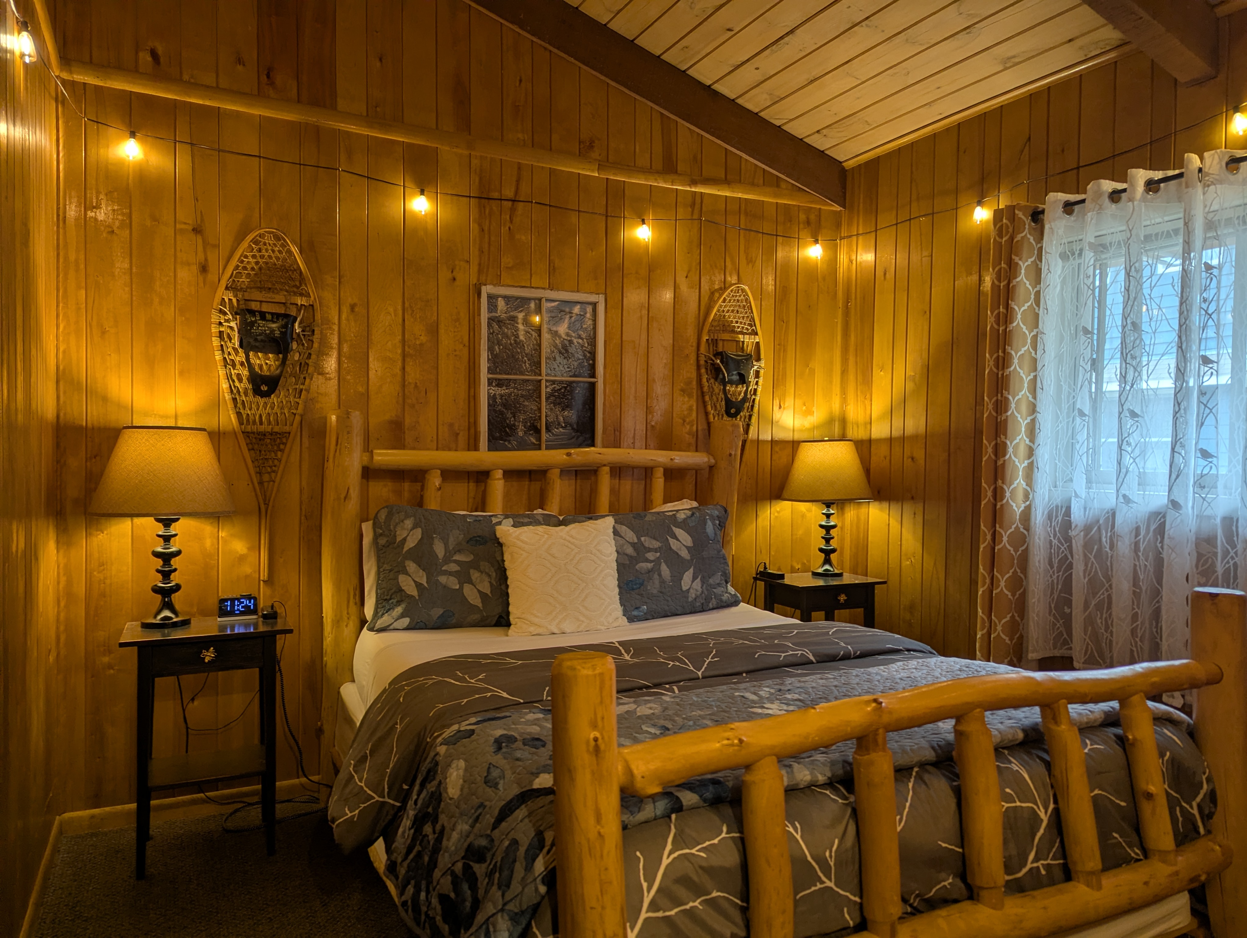 log bedframe with cozy bed and wood paneling