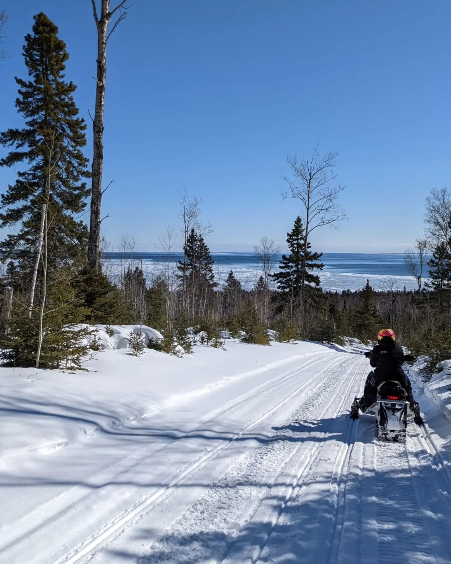 snowmobile rider on trail with lake superior in background